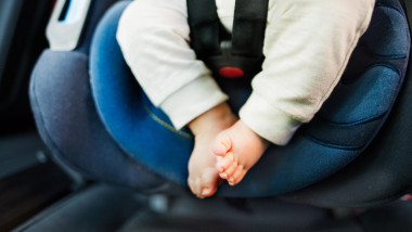 Unrecognizable little baby in safety car seat.