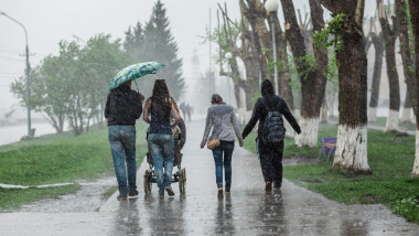 Group of people walking down the street at heavy rain in motion blur. Concept bad weather, resistance to difficulties.