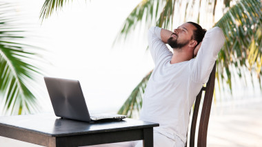 Man relaxing on the beach with laptop, freelancer workplace, dream job