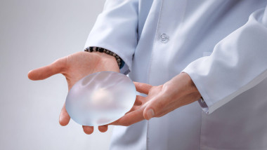 Imagine cu un medic care ține în mână un implant mamar