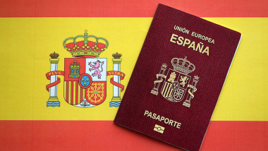 Red Spanish passport of European Union on national flag background close up. Tourism and citizenship concept. Red Spanish passport of European Union