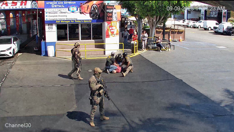 A car wash owner is held down by security forces members during a raid in LA