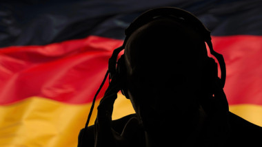 Silhouette of a man in headphones on the background of the flag of Germany, eavesdropping conversation, secret agent, military intervention, coup, spy