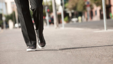 Legs of a businessman walking on sidewalk