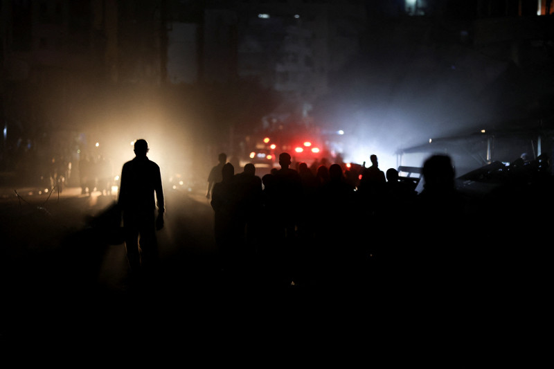 Palestinians walk during a power cut, amid a ceasefire between Israel and Hamas, in Gaza City