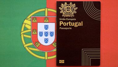 Red Portugal passport of European Union on national flag background close up. Tourism and citizenship concept. Red Portugal passport of European