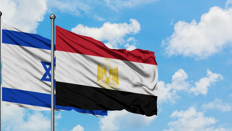 Israel and Egypt flag waving in the wind against white cloudy blue sky together. Diplomacy concept, international relations.