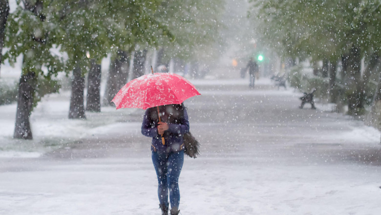Femeie cu umbrelă roșie, ninsoare, alee în parc, București.