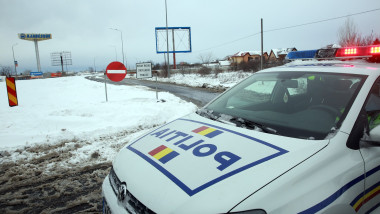 Mașină de poliție pe un drum acoperit de zăpadă, închis circulației din cauza viscolului