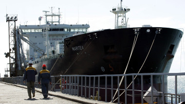 Workers walk past a tanker at the Rosneft oil product transshipment terminal in Tuapse