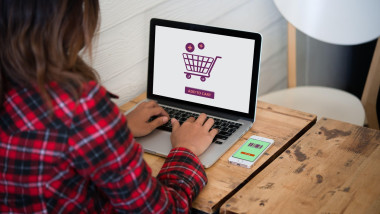 Online shopping website on laptop screen with female hands typing. Freedom shopping e-commerce.