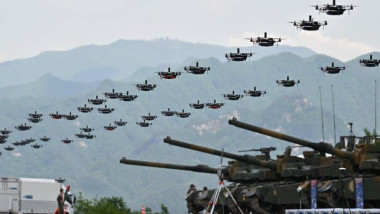 roi de drone care zboară pe deasupra unor tancuri