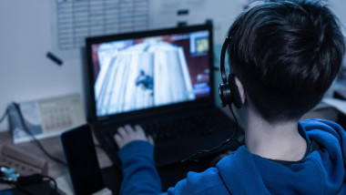 Child gaming on laptop playing addictive online video game at home in his room.