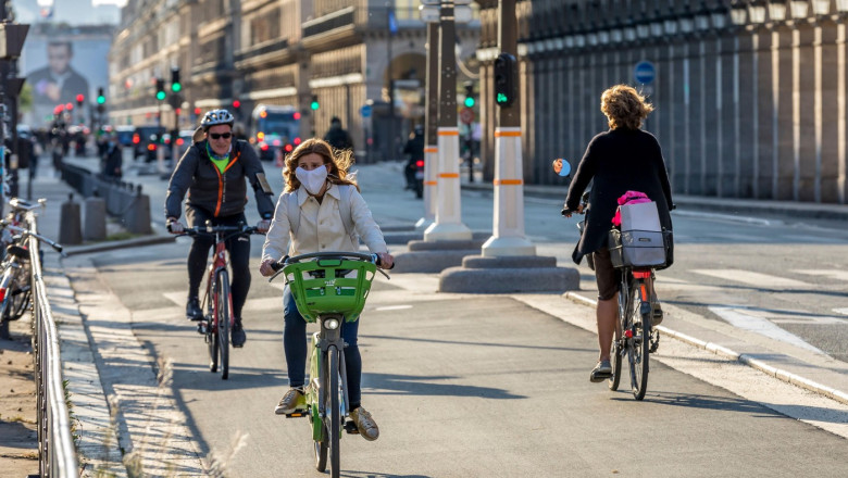 Paris, France - May 14, 2020: Young woman on her bike with a surgical mask to protect herself from covid-19 in a street in Paris