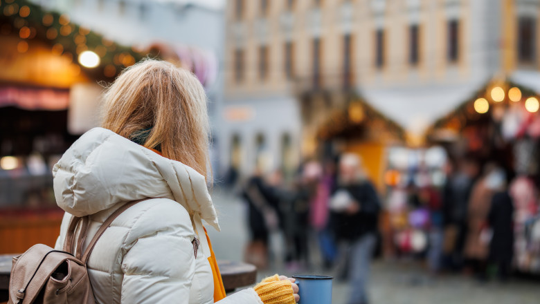 femeie cu o cana in mana la un targ de craciun