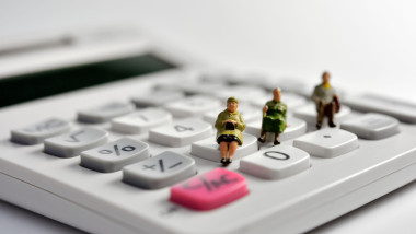 Miniature pensioners sitting on a calculator
