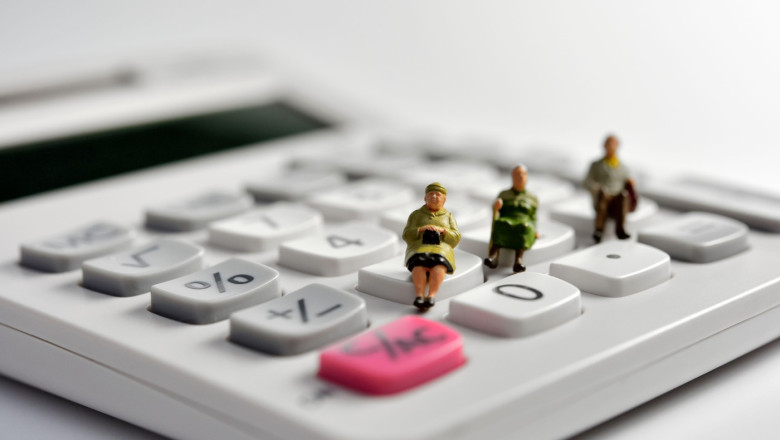 Miniature pensioners sitting on a calculator