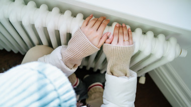 femeie se incalzeste la calorifer