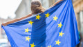 EU Flag. Cute happy girl with the flag of the European Union. Young teenage girl waving with the European Union flag in the city