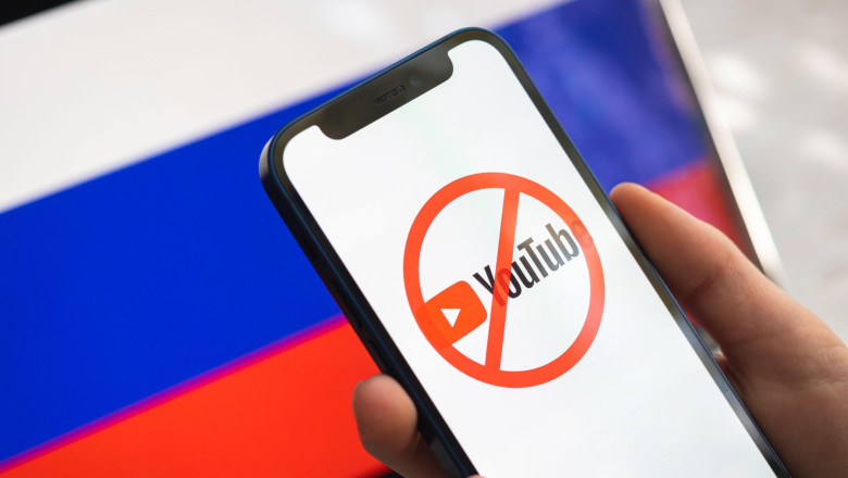 Poltava, Ukraine - March 23, 2022: Youtube and Russia flag. Sanctions, ban and banned business. Youtube logo, big company stopped working in Russian F
