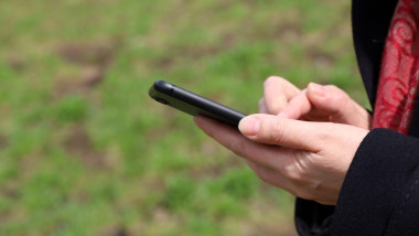 Female hands with smartphone close up. Woman using mobile phone in spring park
