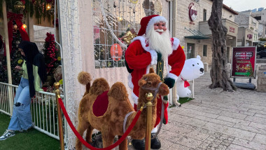 Haifa, Israel, 3 December 2025, Santa claus figure standing next to a decorative camel on a street in haifa during the holiday season