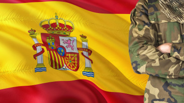 Crossed arms Spanish soldier with national waving flag on background - Spain Military theme.