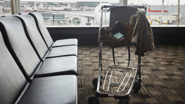 Smartphone in shoulder bag in luggage trolley in airport lounge