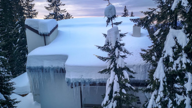 Small modern lodge or cabana covered in snow, surrounded by icy evergreens overlooking the Carpathian Mountains