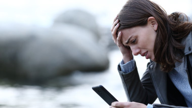 Sad woman complaining checking mobile phone on the beach