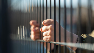 Child refugee hand holding a metal fence. Social problem of war migrants.