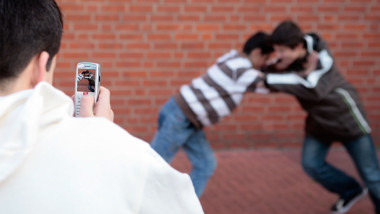 two boys fighting and being filmed by another one