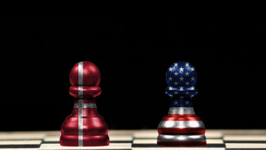 Close up to a two pawns chess pieces with the flags of denmark and united states over a chess board and black background in geopolitical concept
