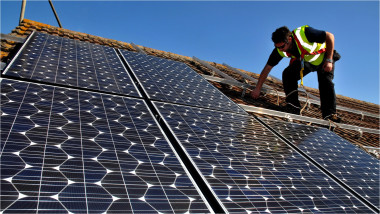 un instalator montează panouri solare pe acoperișul unei case