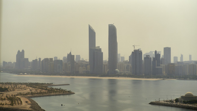Aerial view of a hazy city skyline with tall buildings and a waterfront. Abu Dhabi, UAE