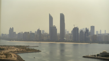 Aerial view of a hazy city skyline with tall buildings and a waterfront. Abu Dhabi, UAE
