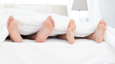 Couple showing their feet while lying on a bed