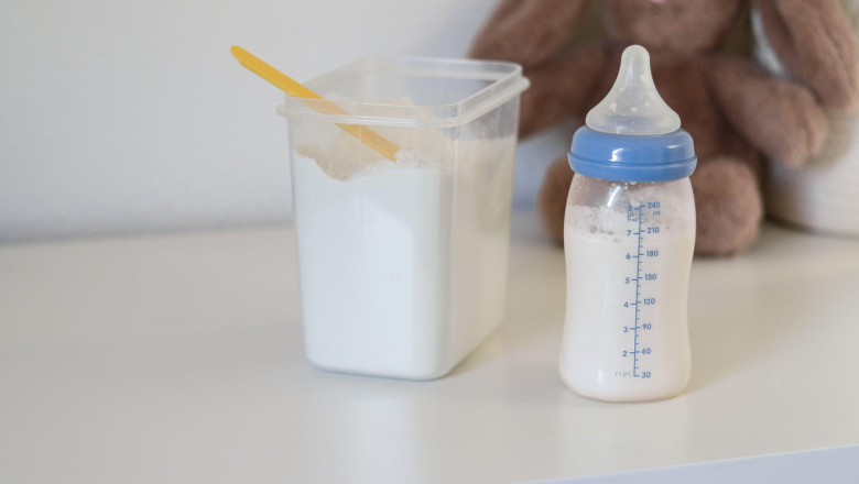 Close up of a feeding bottle with baby formula milk on white table