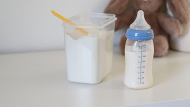 Close up of a feeding bottle with baby formula milk on white table