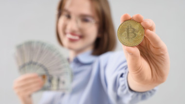 Young woman with bitcoin and dollar banknotes on light background, closeup