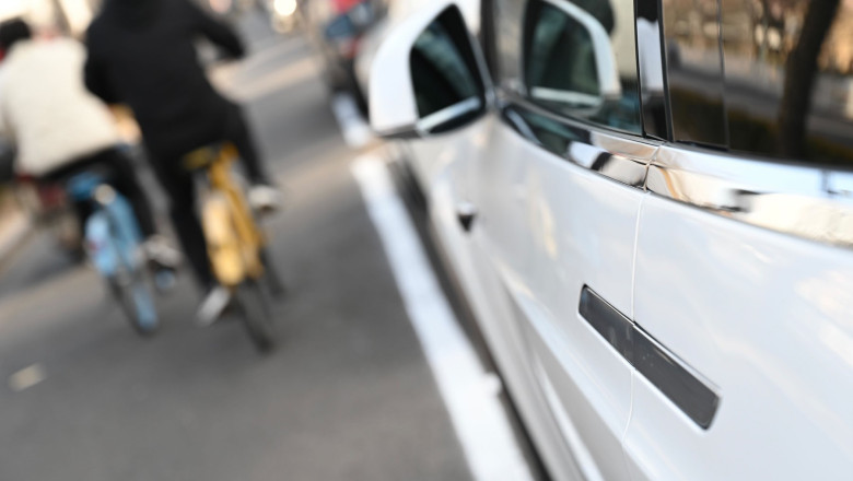 masina electrica si biciclist trece pe langa ea