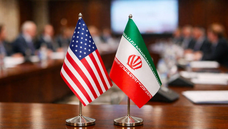 Two small national flags of the United States and Russia placed on a conference table, with a blurred background of an important international meeting