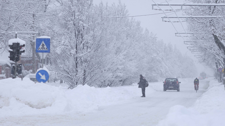 om traverseaza strada acoperita de zapada mare, ninge