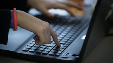 copil scrie la tastatura laptopului