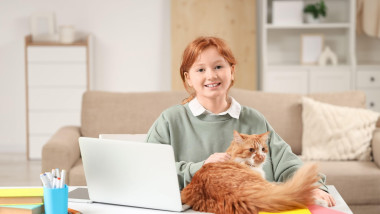 Redhead teenage girl with cute cat studying at home