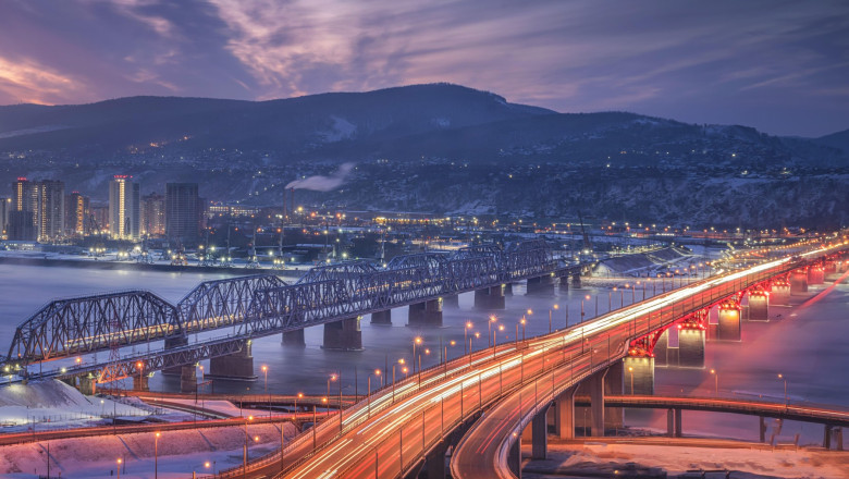 Evening panorama of Krasnoyarsk. Nikolaevsky 4th bridge and railway bridge over the Yenisei River at dawn. A stunning view of a vibrant city at dusk,
