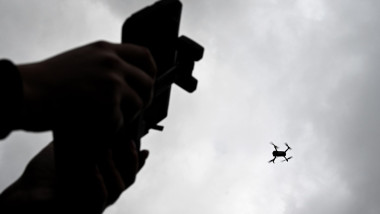 Drone is flying in the sky. Operator controls the drone.