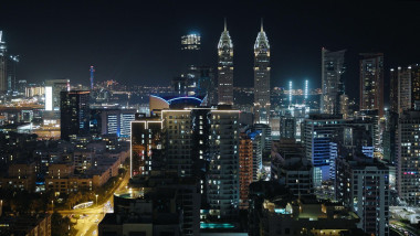 Dubai by night, city skyline with The Business Central Towers, illuminated highways, and modern glass and steel skyscrapers, aerial view.