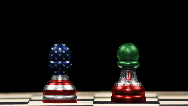Close up to a two pawns chess pieces with the flags of united states and iran over a chess board and black background in geopolitical concept