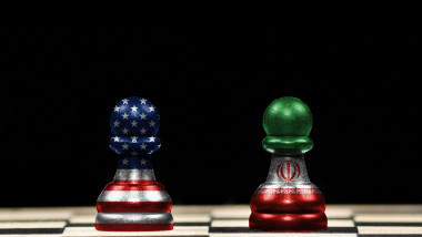 Close up to a two pawns chess pieces with the flags of united states and iran over a chess board and black background in geopolitical concept